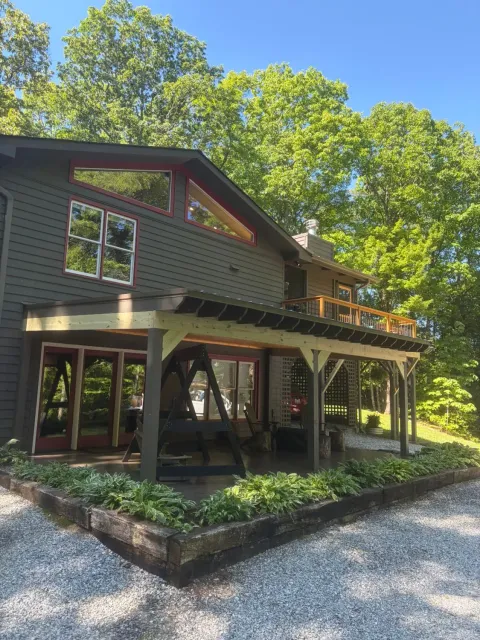 Covered patio and awning extension with a metal roof on a gray mountain home in Cashiers, North Carolina