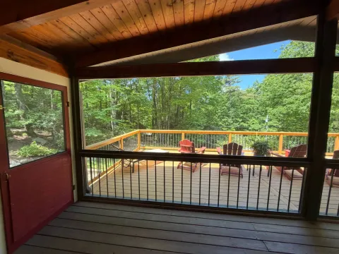 View from a screened porch onto a new wood deck with metal balusters in Cashiers, North Carolina