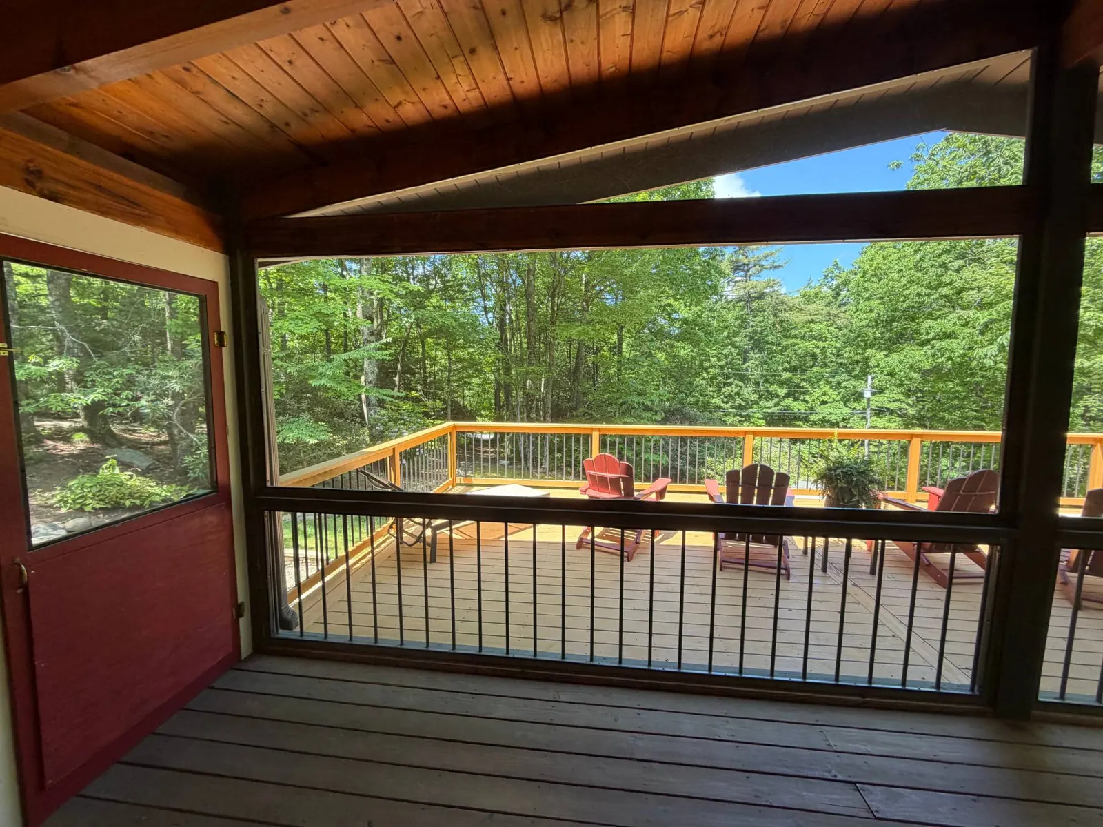 View from a screened porch onto a new wood deck with metal balusters in Cashiers, North Carolina