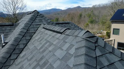 Close view of charcoal shingle hips and dormer with mountains behind