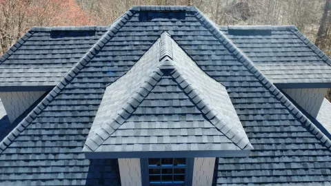 Charcoal dimensional shingle hip roof with ridge cap over a dormer