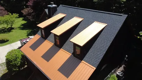 Aerial view of charcoal shingles with copper-tone metal dormer caps and porch roof
