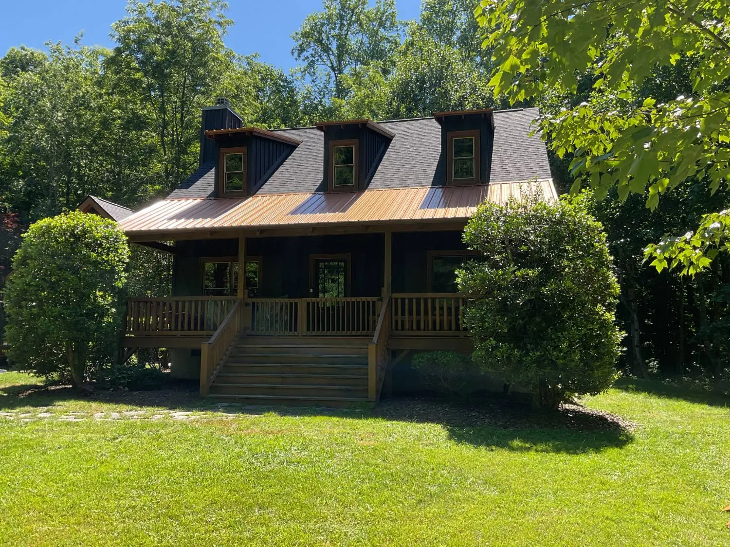 Mountain cabin with charcoal dimensional shingles, three dormers and a copper-tone metal porch roof
