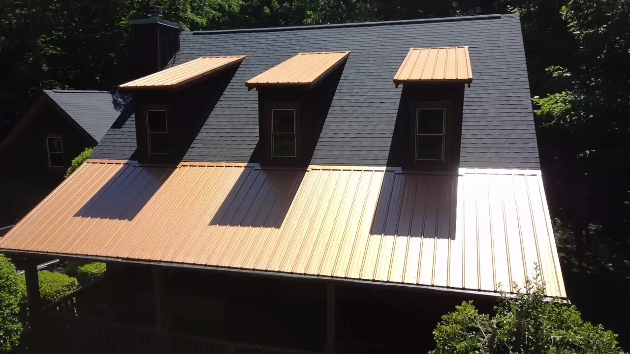 Copper-tone metal porch roof and dormer caps against charcoal dimensional shingles