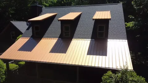 Copper-tone metal porch roof and dormer caps against charcoal dimensional shingles