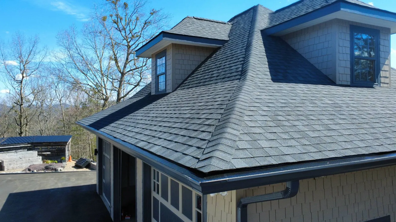 Charcoal shingle roof edge with seamless gutters, mesh gutter guards and a dormer