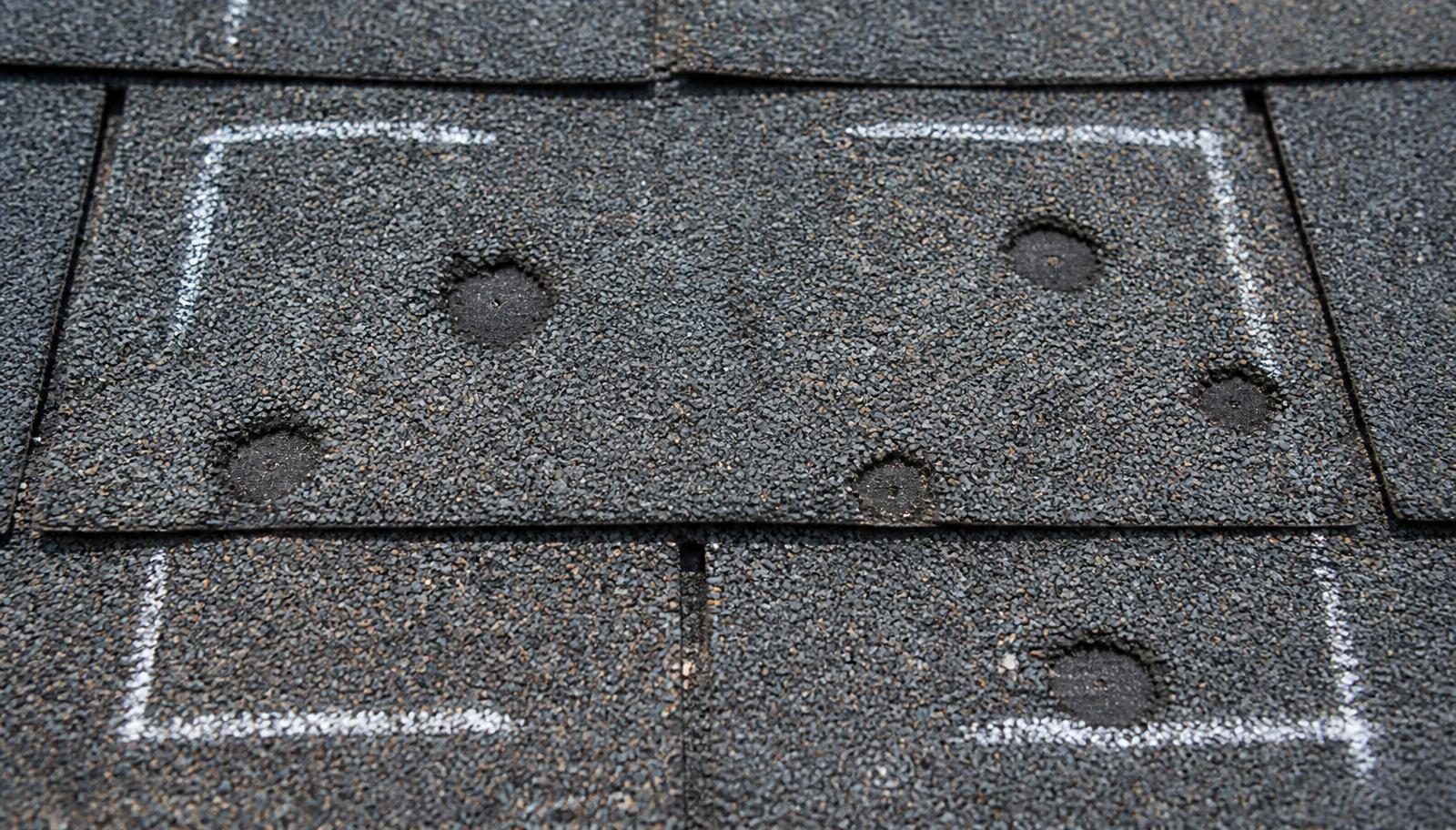 Hail damage to asphalt shingles showing granule loss and exposed mat on a Western North Carolina roof